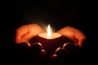 Hands cupping around a candle for an accident victim